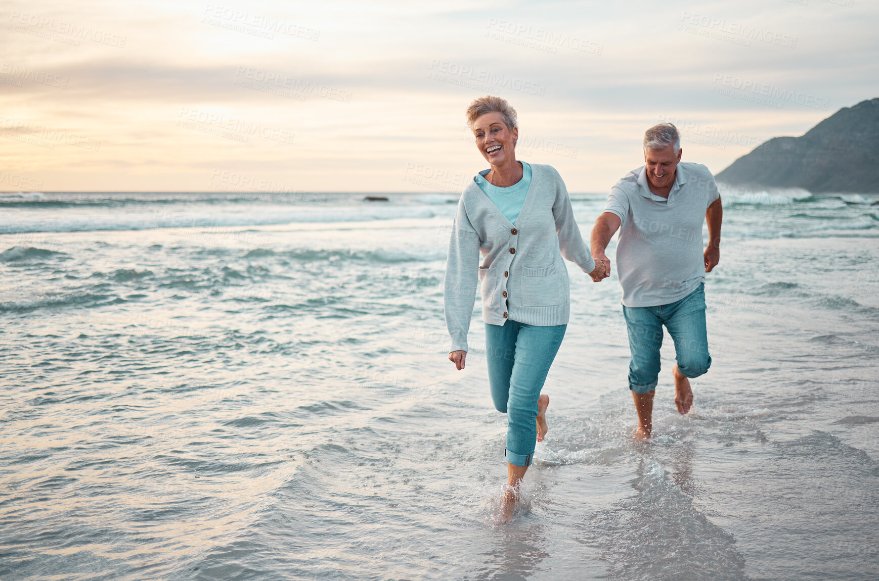 Buy stock photo Beach, walking and senior couple holding hands for support, love and care with outdoor wellness, retirement and holiday lifestyle with sunset sky. Elderly people running together in sea ocean water