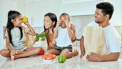 Buy stock photo Asian, vegetables and family in kitchen for playing at table, happy or together for bonding. Mom, dad and children with smile at counter for health, food or nutrition with bags after shopping in home
