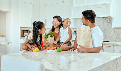 Buy stock photo Asian, family and vegetables in kitchen for laugh at table, happy or comic in bonding. Mom, dad and children with smile at counter for funny, joke or crazy with bags after shopping in home in Jakarta