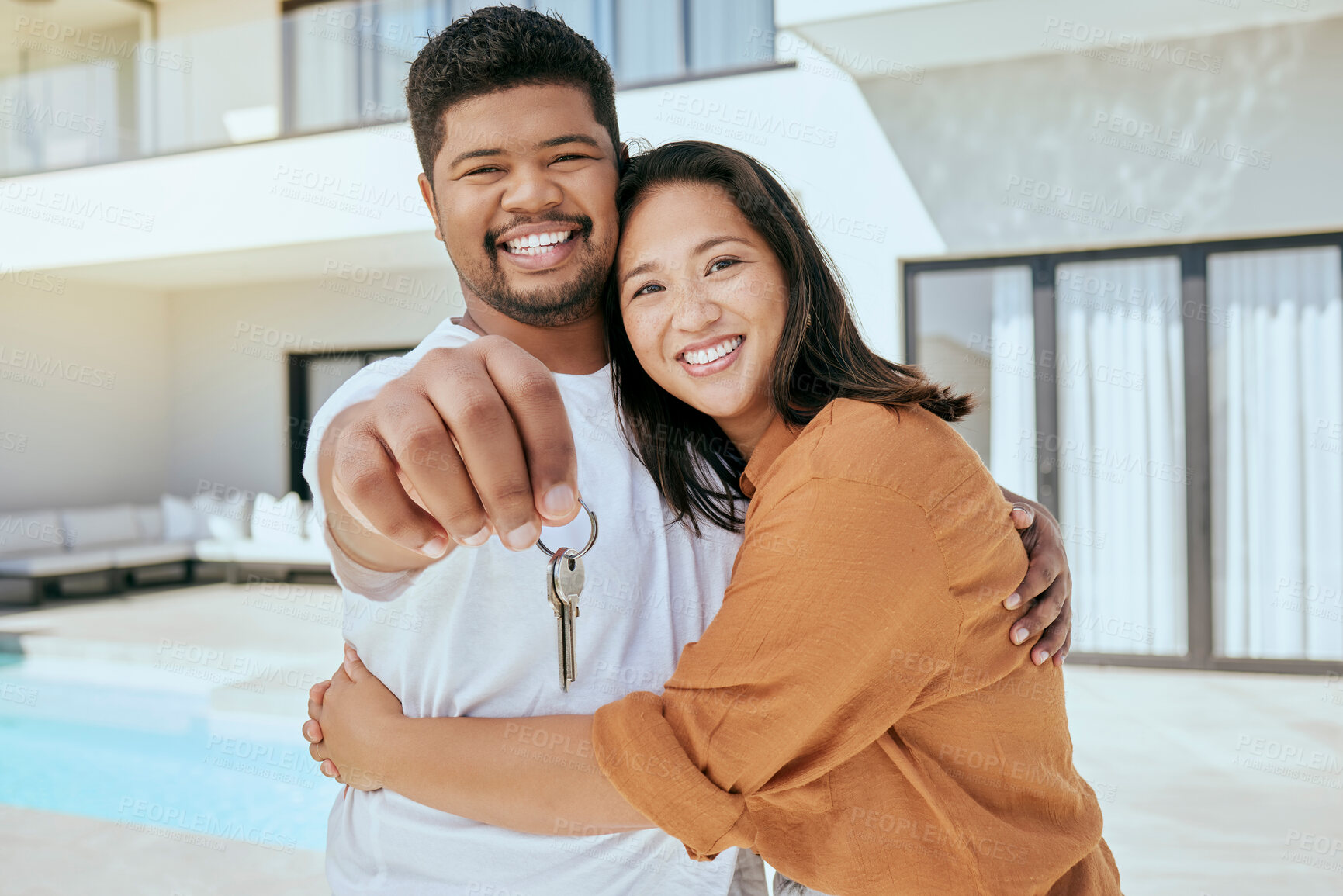 Buy stock photo Homeowner, couple and show keys to new house, being happy and successful with smile, relax and hug. Portrait, black man and Asian woman celebrate, on property investment and embrace together outdoor.