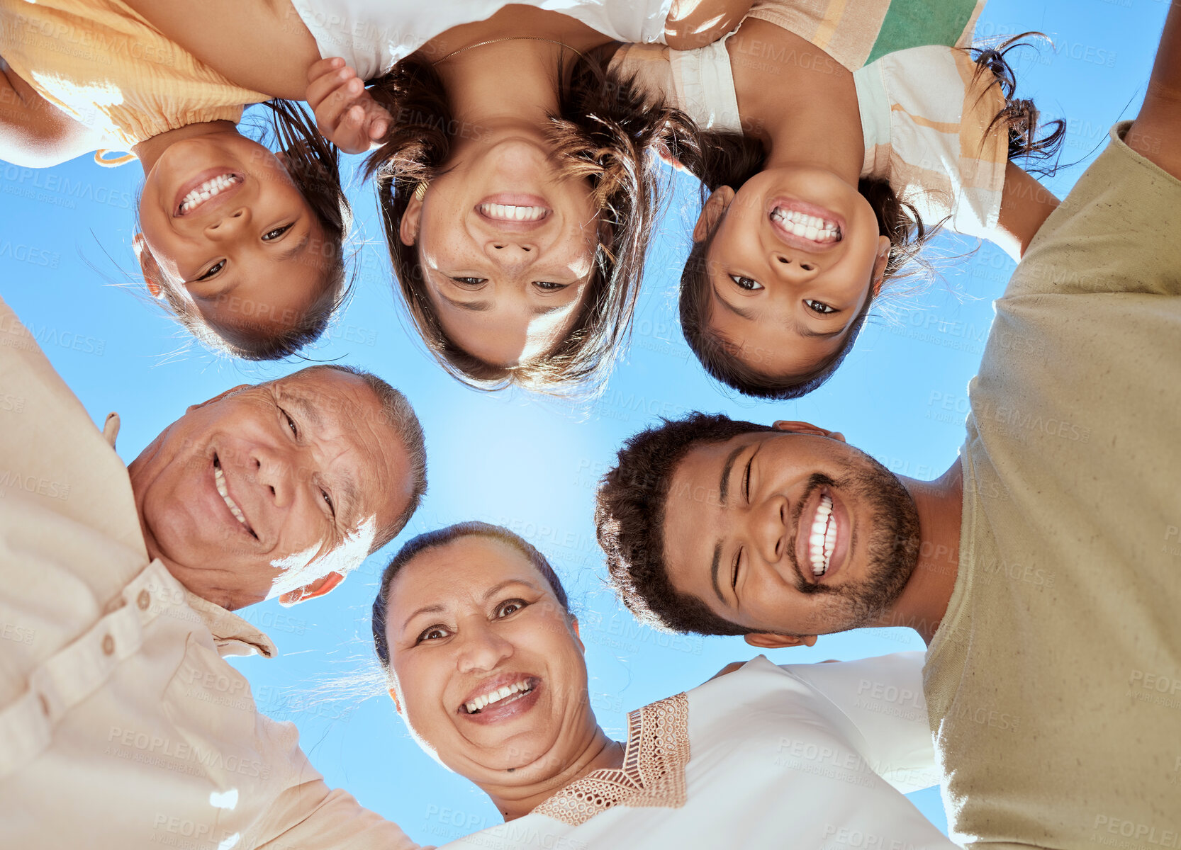 Buy stock photo Huddle, below and big family with love, care and support together in nature against a blue sky. Grandparents, children and portrait of parents with trust, happy and smile on a holiday to relax