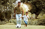 Father, child and playing with soccer ball in the park for fun quality bonding time together in nature. Dad and kid enjoying family weekend, break or exercise for playful summer of soccer outside