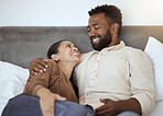 Love, relax and couple in bed in their home, resting and smiling while talking and bonding in bedroom together. Black family, resting and comfort with smile, happy and laughing man and woman embrace