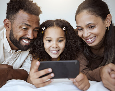 Buy stock photo Black family, phone and child on bed for video, smile or happy for streaming, cartoon or movie. Mom, dad and kid with smartphone in bedroom to game, internet or watching to relax, happiness or play