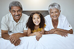 Happy, grandparents and child lying on bed with smile for family bonding, retirement and relax at home. Portrait of little girl, grandma and grandpa smiling in bedroom relaxing together for childcare