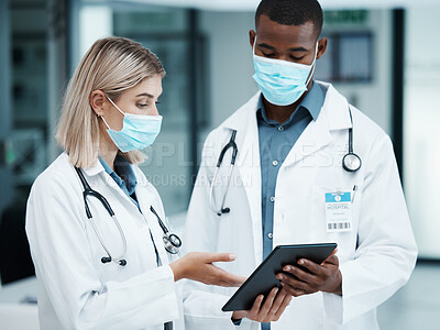 Buy stock photo Healthcare, covid and doctors checking tablet for medical data, patient chart or insurance documents in hospital lobby. Face mask, man and woman working in medicine consulting internet before surgery