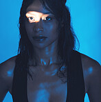 Spotlight, beauty and model in a neon studio posing for trendy beauty, cosmetics or skincare. Young, beautiful and woman from Mexico with a light reflection on her face isolated by a blue background.