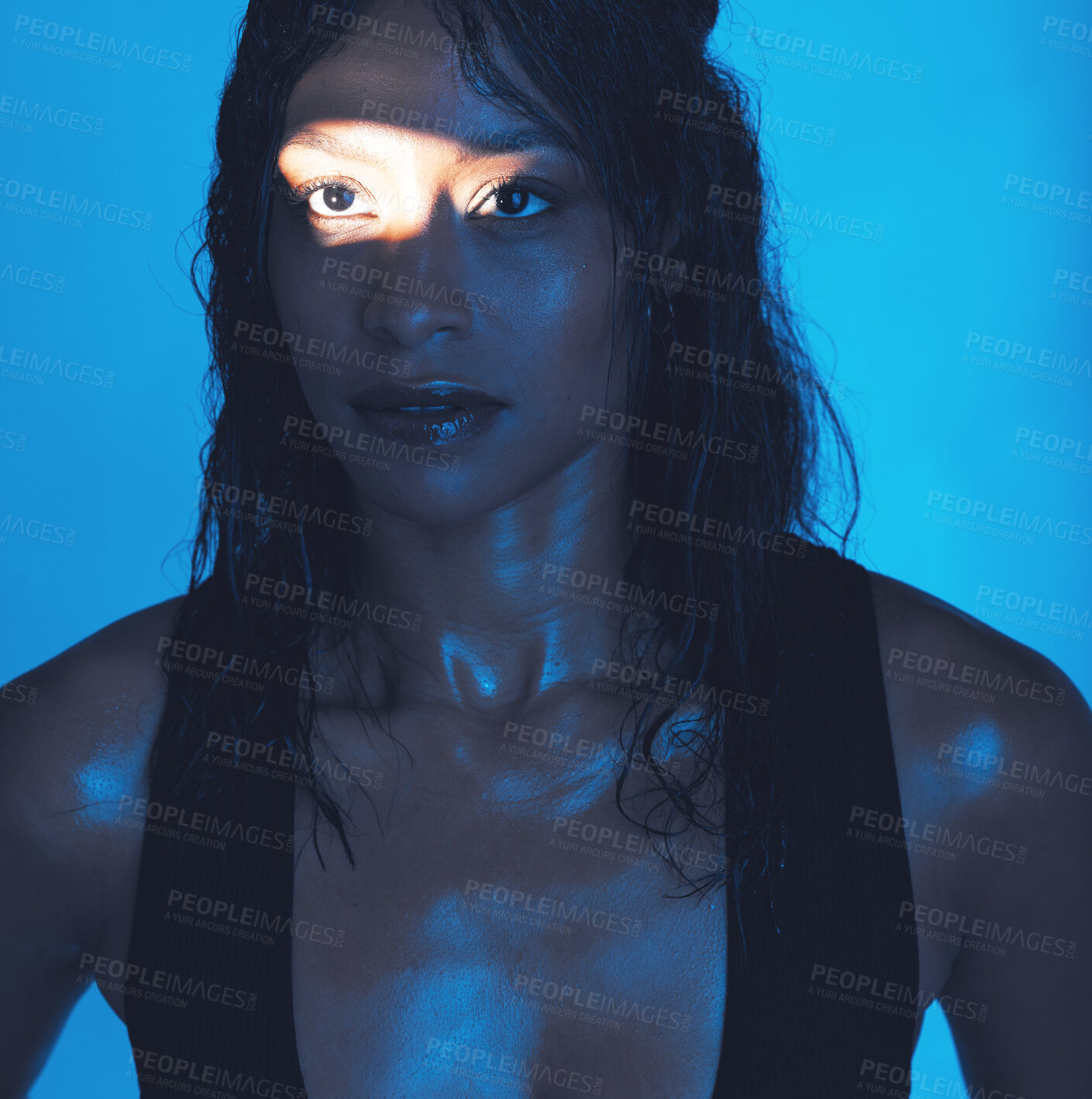 Buy stock photo Spotlight, beauty and model in a neon studio posing for trendy beauty, cosmetics or skincare. Young, beautiful and woman from Mexico with a light reflection on her face isolated by a blue background.