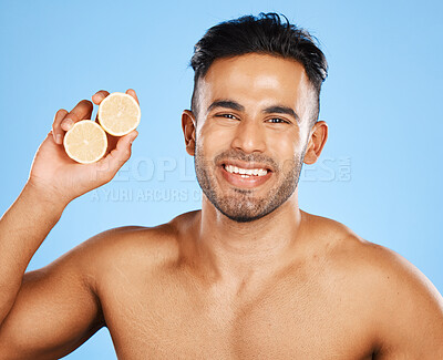 Buy stock photo Face, skincare and orange with a man model in studio on a blue background to promote natural beauty. Portrait, fruit and wellness with a handsome young male posing for a health product or treatment