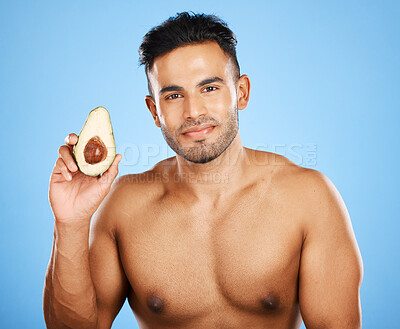 Buy stock photo Beauty, skincare and man with avocado for health, wellness and nutrition on blue background. Healthy food, body care and portrait of young and happy male model from Canada with clean glowing skin.

