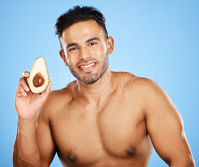 Buy stock photo Beauty, skincare and avocado with a model man posing in studio on a blue background for health or wellness. Portrait, diet and antioxidants with a handsome young male posing to promote natural care
