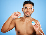 Floss, dental care and portrait of man on blue background studio for hygiene, health and cleaning teeth. Dental healthcare, healthy mouth and young model holding dental floss for morning routine