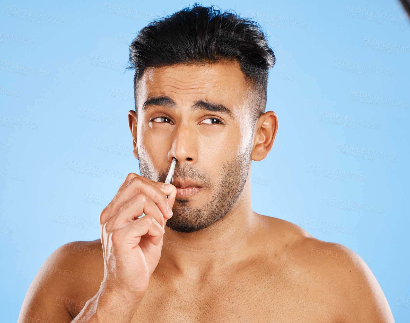 Buy stock photo Beauty, hair and nose tweezers with man in a studio for cleaning, wellness and skincare against a blue background. Face, hair removal and mexican model grooming, hygiene and tweezer pamper treatment