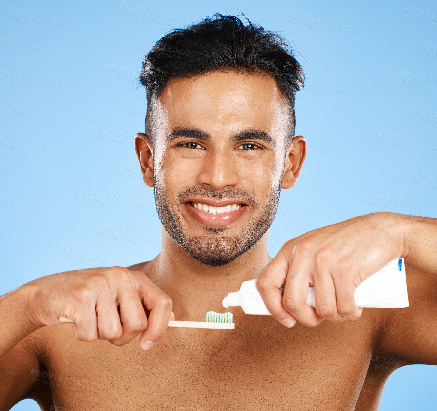 Buy stock photo Mouth, dental and man brushing teeth in studio for wellness, health and grooming on blue background. Portrait, face and teeth of indian guy happy with oral cleaning product, toothpaste and mockup