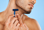 Man, hands and shaving with razor for beard grooming, skincare or facial treatment against a blue studio background. Hand of male in beauty shave for face, skin or cosmetic care for clean hygiene