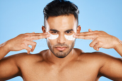 Buy stock photo Man, eye patches and beauty for skincare, cosmetics or facial products against a blue studio background. Portrait of isolated male model in care for eyes applying patch for healthy skin or treatment