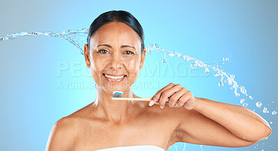 Buy stock photo Dental, health and woman brushing teeth with toothbrush, toothpaste and water splash on blue studio background. Healthcare, self care product and oral care hygiene of mature Brazilian beauty model.
