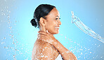 Beauty, skincare and splash of water with woman for health, hydration and spa moisture. Wellness, smile and shower with side profile of model against blue background for natural, cosmetics and relax