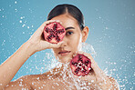 Beauty, skincare and woman with pomegranate in face, splash and natural treatment for fresh, clean and glowing skin. Water, fruit and healthy cosmetics for beautiful model girl with studio background