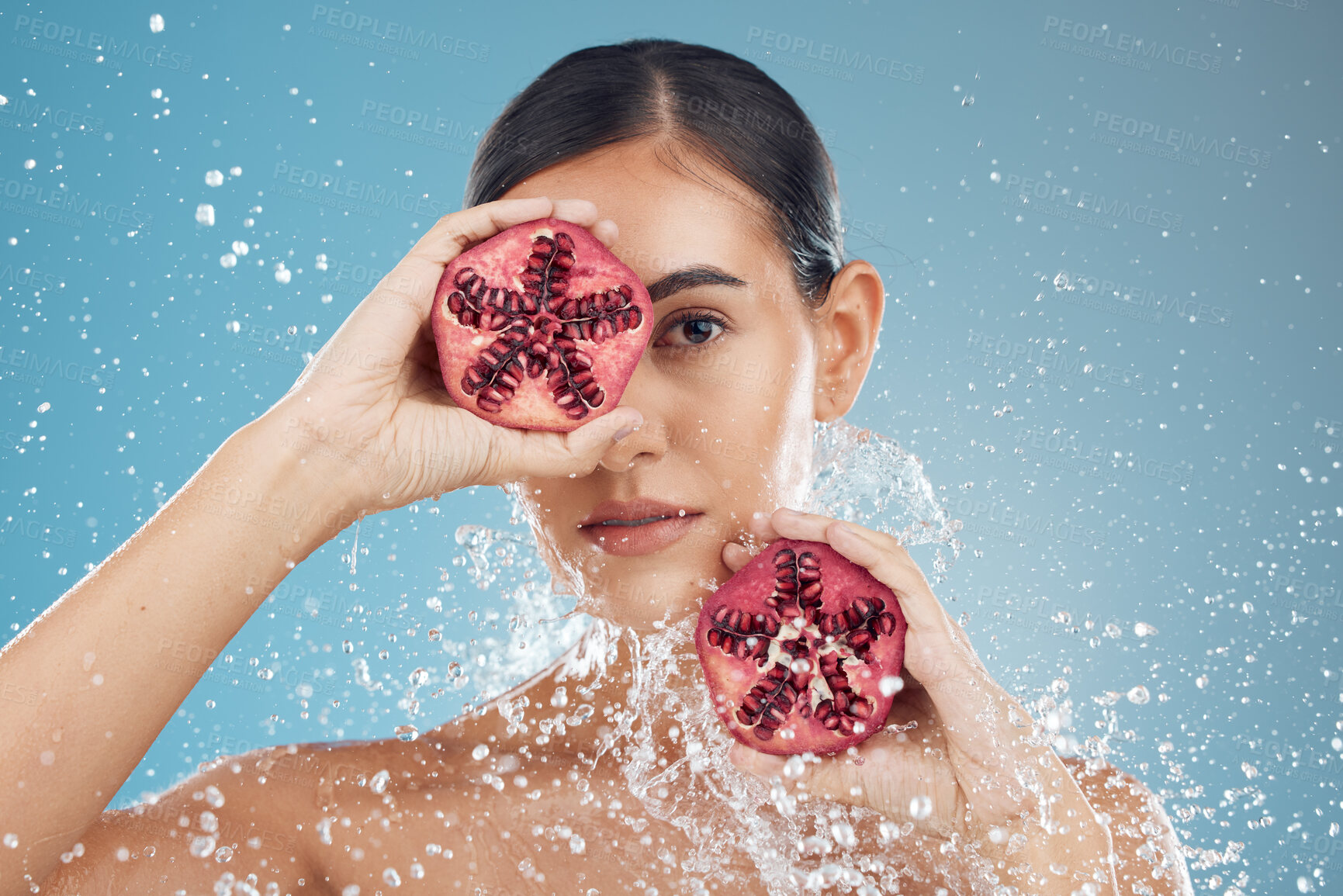 Buy stock photo Beauty, skincare and woman with pomegranate in face, splash and natural treatment for fresh, clean and glowing skin. Water, fruit and healthy cosmetics for beautiful model girl with studio background