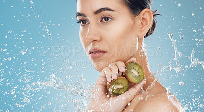 Buy stock photo Beauty, water and kiwi with a model woman posing in studio on a blue background for natural skincare with a splash. Food, wet and luxury with an attractive female posing to promote health or wellness