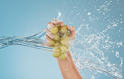 Buy stock photo Hand, grapes and water by woman in studio for wellness, health and nutrition mockup, studio and blue background. Splash, fruit and model hands for plant, organic and nutrition skin, product and diet 