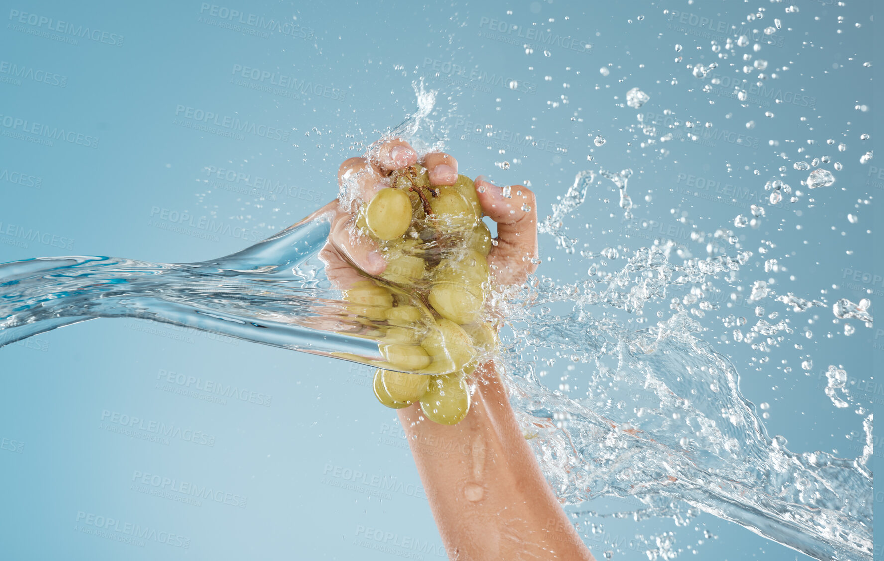 Buy stock photo Hand, grapes and water by woman in studio for wellness, health and nutrition mockup, studio and blue background. Splash, fruit and model hands for plant, organic and nutrition skin, product and diet 