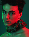 Beauty, snake and model in a studio with neon light of green and red color posing with a serpent. Skincare, face and man from Mexico standing with a reptile on his neck isolated by a green background