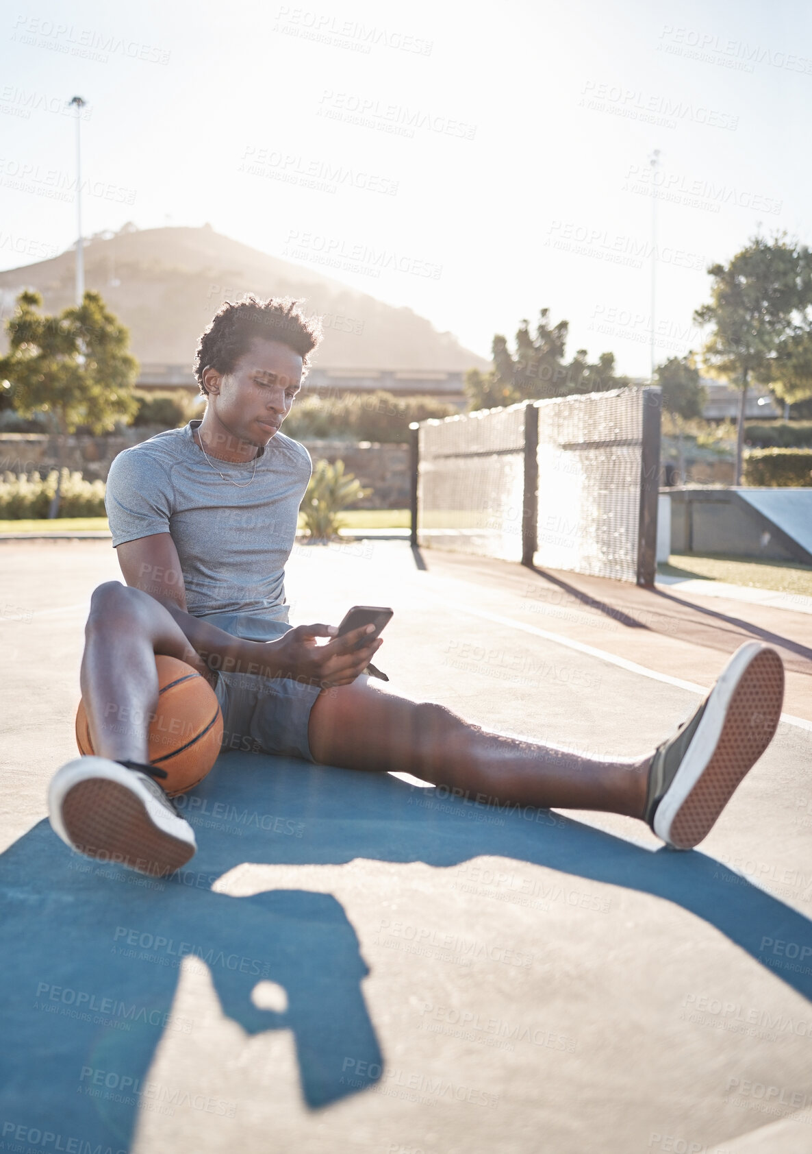 Buy stock photo Basketball, phone and man relax on social media, internet and reading news on app outdoor on a court. Black man with 5g smartphone after sport training, exercise and game at sports club in summer