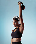 Fitness, music and woman lifting a kettlebell in studio strength training, sports workout and full body exercise. Healthy, sports and Indian girl with strong arms streaming a podcast audio or radio 
