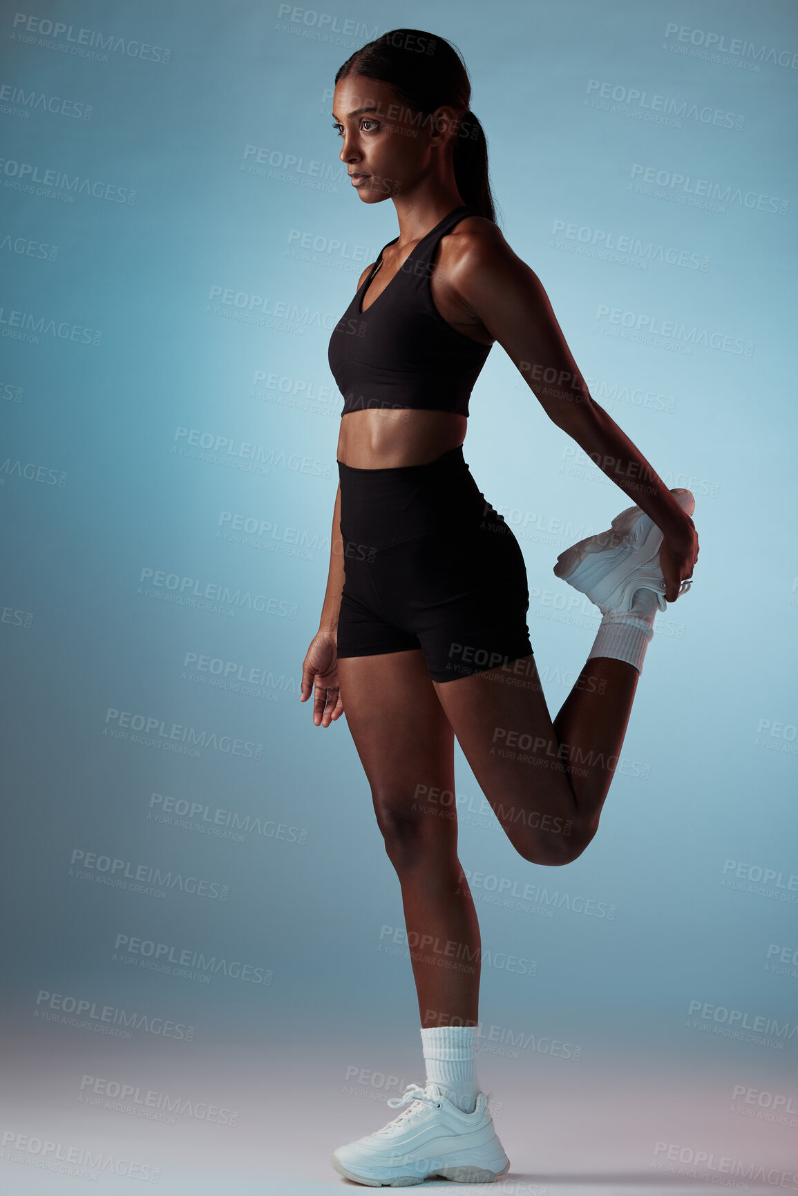 Buy stock photo Fitness, exercise and black woman stretching her leg in studio before sports training or workout. Healthy, athlete and slim African model doing warm up in sportswear while isolated by blue background