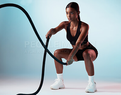 Buy stock photo Woman, battle rope or training on blue background in studio for exercise, training or workout for strong arm muscles. Personal trainer, sports person or fitness model in cardio or energy gym wellness