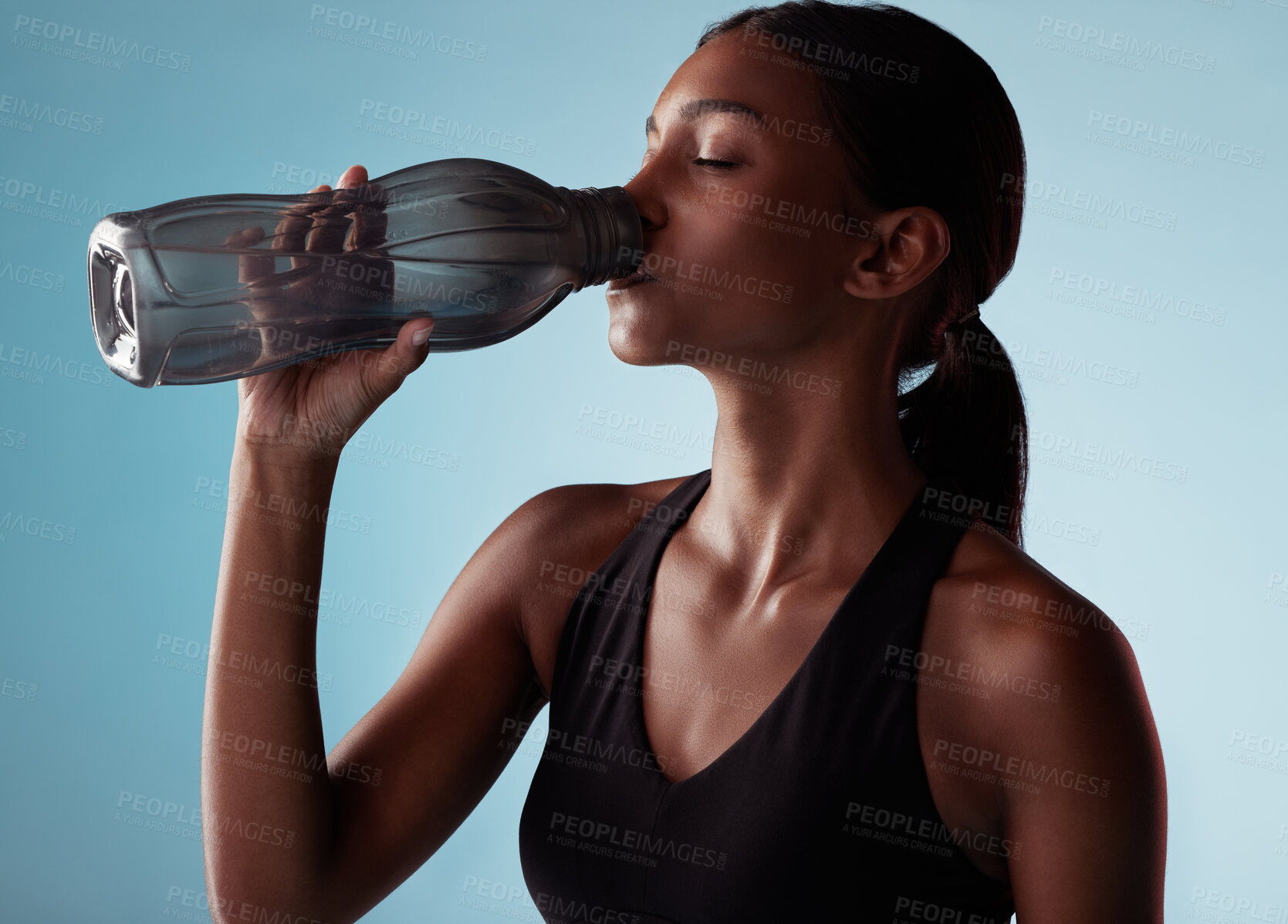 Buy stock photo Fitness, sports and woman drinking water in studio for a healthy body after training, cardio workout and exercise. Wellness, blue background and thirsty girl enjoys a beverage to hydrate or hydration