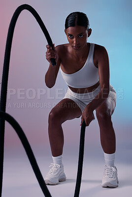 Buy stock photo Rope, cardio and woman training for health, fitness and wellness against a colourful studio background. Strong, focus and Indian athlete with battle ropes for exercise, motivation and workout