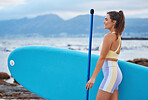 Woman, happy and surfboard relax on beach for sports exercise wellness on travel vacation. Young athlete surfer, freedom smile and thinking for peace or mental health on rocks outdoors with blue sky