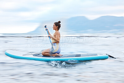 Buy stock photo Paddle board, sea and fitness with a sports woman floating on water in nature for wellness or exercise. Earth, training and travel with a female athlete on a paddleboard while on vacation for travel