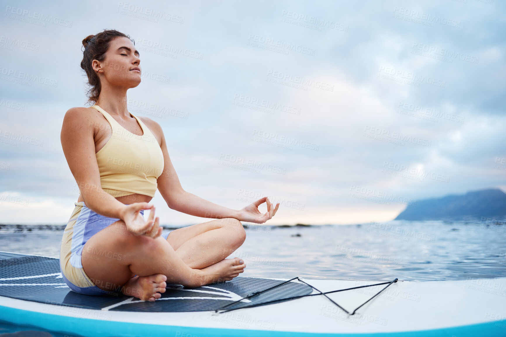 Buy stock photo Meditation, surf and sea with a woman on a surfboard floating out in nature with a cloudscape and mockup. Yoga, ocean and zen with a young female meditating for health, wellness or balance outside