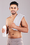 Fitness, exercise and portrait of man with towel on shoulders for wellness, sports and workout. Healthy lifestyle, training and young male with water bottle in hand isolated on gray background studio