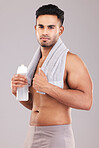 Portrait, water bottle and man with towel, for wellness and workout with grey studio background. Indian male focus, healthy trainer or exercise for fitness, training or motivation being relax or rest
