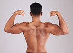 Fitness, back muscle flexing and man isolated on gray studio background. Wellness, sports and body builder showing off biceps during training, workout or exercise for body strength, energy or power.
