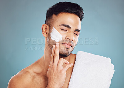 Buy stock photo Face, skincare cream and man facial morning routine for beauty care. Young Indian person, hydrate skin treatment and grooming wellness or healthy dermatology bodycare in blue background studio

