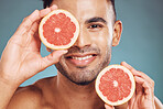 Man, face and grapefruit skincare natural citrus beauty treatment. Facial wellness. healthy lifestyle and portrait of happy male fruit healthcare or cosmetic skin detox against blue background studio