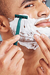 Shaver, foam and man shaving his beard for hygiene, health and smooth skin in a studio. Razor, clean and handsome guy from India grooming his facial hair for dermatology wellness or a face treatment.
