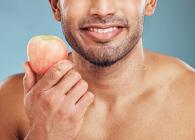 Buy stock photo Face, skincare and man with apple for health, vitamin c and nutrition on blue studio background. Wellness, healthy lifestyle or bearded model holding fruit for minerals, natural skin or facial care

