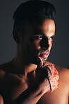 Face, fighting and blood with a man in studio on a gray background ready for a competitive fight. Sports, MMA and boxing with the hand of a young male in a bandage during a brawl or altercation