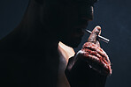 Injury, cigarette and blood bandage on hand of kickboxing man in studio for shadow, art deco and bad habits background. Male champion boxer smoking after fighting in MMA violence sports competition