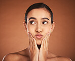 Woman with kiss lips, natural makeup on brown studio background and luxury skincare in dermatology spa. Latino girl with model pose, cosmetics beauty with lipstick and apply sunscreen cream to face