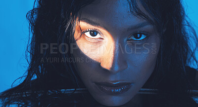 Buy stock photo Beauty, cosmetics and portrait of a model with a light reflection on her face in the studio. Spotlight, skincare and young woman from Puerto Rico with natural skin isolated by a blue background.