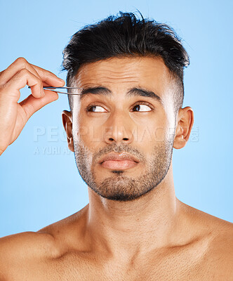 Buy stock photo Face, hair removal and man in studio with tweezer for skincare, beauty and eyebrow on blue background. Tweezing, wellness and indian model shape eyebrows for grooming, hygiene and cleaning on mockup