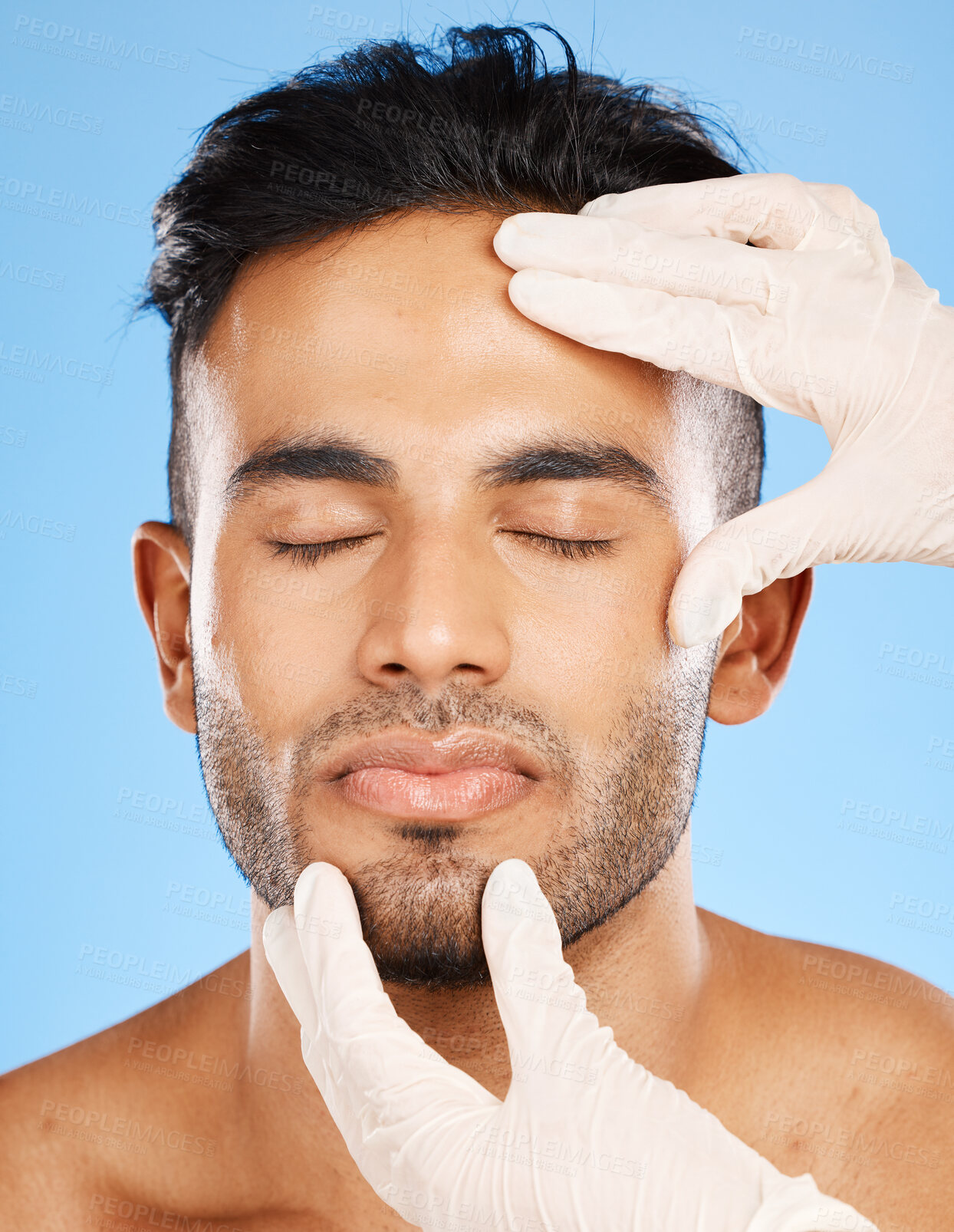 Buy stock photo Plastic surgery, man and cosmetics for face, skincare or natural beauty against blue studio background. Young male, white gloves or organic facial for smooth, glow skin and hydration for rejuvenation